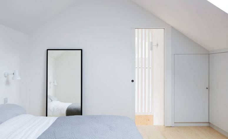 06-The-bedroom-is-clam-and-peaceful-with-light-colored-wooden-floors-and-white-walls-only-a-bed-and-a-mirror-are-here-775x475